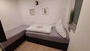 A small, cozy room with a bed, a bench, and two framed motivational quotes on the wall. - Monteurwohnung Inkl. Wlan, Smart-tv, Küche, Waschmaschine, Parkplatz (Roding)