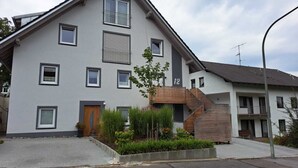 A modern two-story residential building with a grey facade, multiple windows, and a wooden staircase leading to a balcony. - Monteurwohnung Inkl. Wlan, Smart-tv, Küche, Waschmaschine, Parkplatz (Roding)