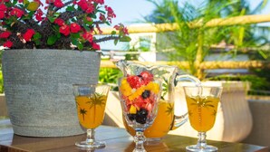 A table with a pitcher of iced tea, two glasses of the same beverage, and a glass of fruit salad. - Casa Mar Self Jeri (Jijoca de Jericoacoara)