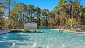 A swimming pool with clear water, surrounded by trees and a fenced area with lounge chairs. - Lakefront 2BR Beach Villa! GOLF CART, Near Beach, Pool, Tram, Screened Porch. (Miramar Beach)