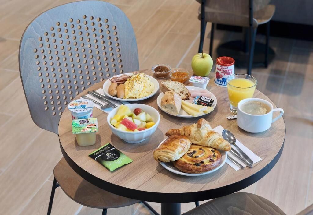 A breakfast table with various food items including yogurt, fruit, bread, and pastries.