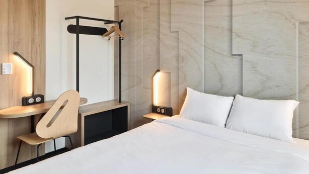 A modern hotel room with a bed, bedside tables, a desk, a chair, and a wall-mounted rack. - B&B Hotel Brest Porte De Gouesnou (Gouesnou)