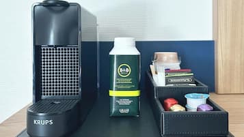 Un altavoz portátil negro, una botella de agua mineral de B&B Hotels y un neceser negro con artículos de aseo.