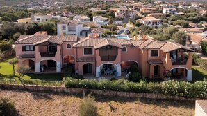 Una casa de varios pisos con un patio, rodeada por un barrio residencial y montañas al fondo.