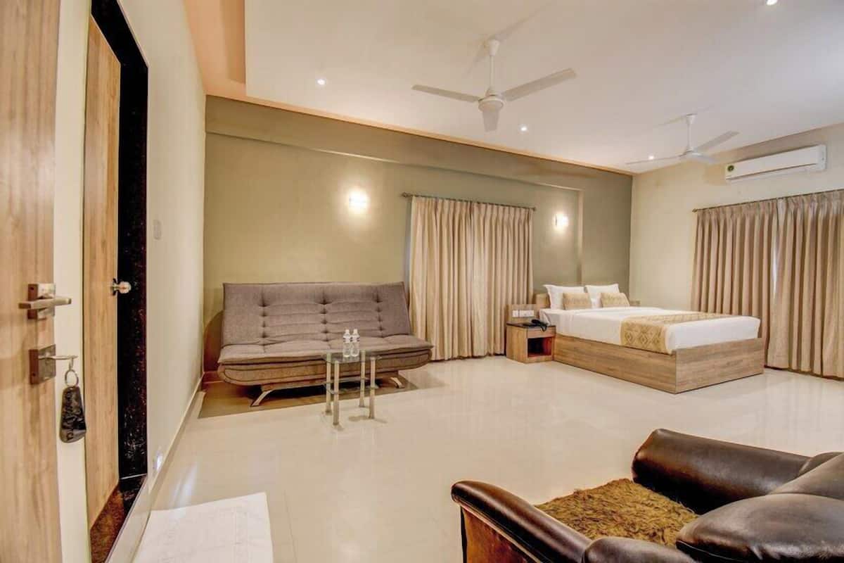 A modern hotel room with a sofa, a bed, a small table, and a ceiling fan.