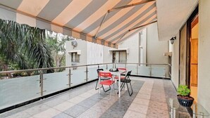 Ein Balkon mit Tisch, Stühlen, einem Blumentopf und einem Geländer.