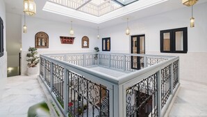 A spacious atrium with a high ceiling, a glass skylight, and a central open area with a white marble floor. - Free People Riad and Spa (Marrakech)