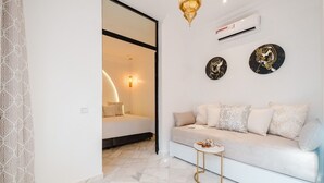 A modern living room with a sofa, a small side table, and decorative wall art. - Free People Riad and Spa (Marrakech)