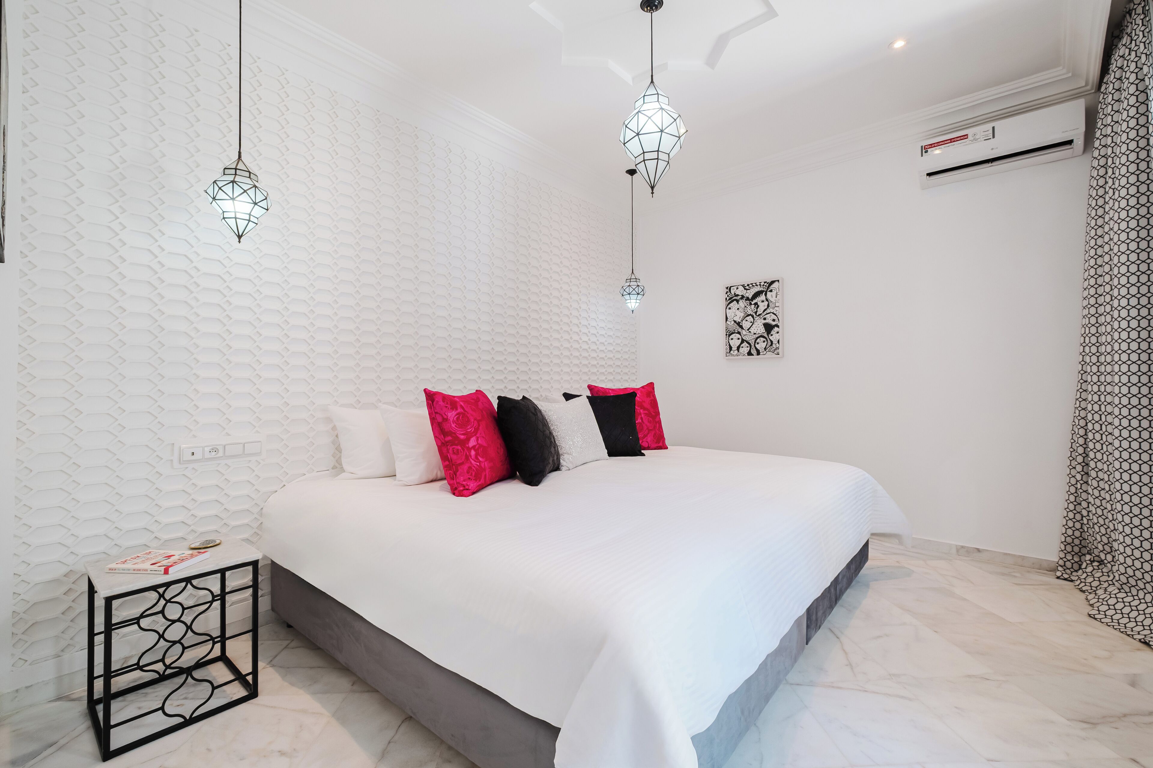 A modern bedroom with a large bed, white textured walls, and geometric patterned curtains.