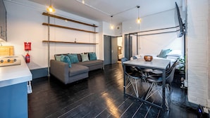 A modern living room with a sofa, a dining table, and hanging lights. - Stylish 1 Bedroom Flat - Sleeps 4 (London)