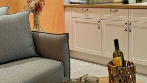 Un salon moderne avec un canapé gris, une petite table ronde sur laquelle se trouve un plateau, deux verres en cristal et une bouteille de vin.
