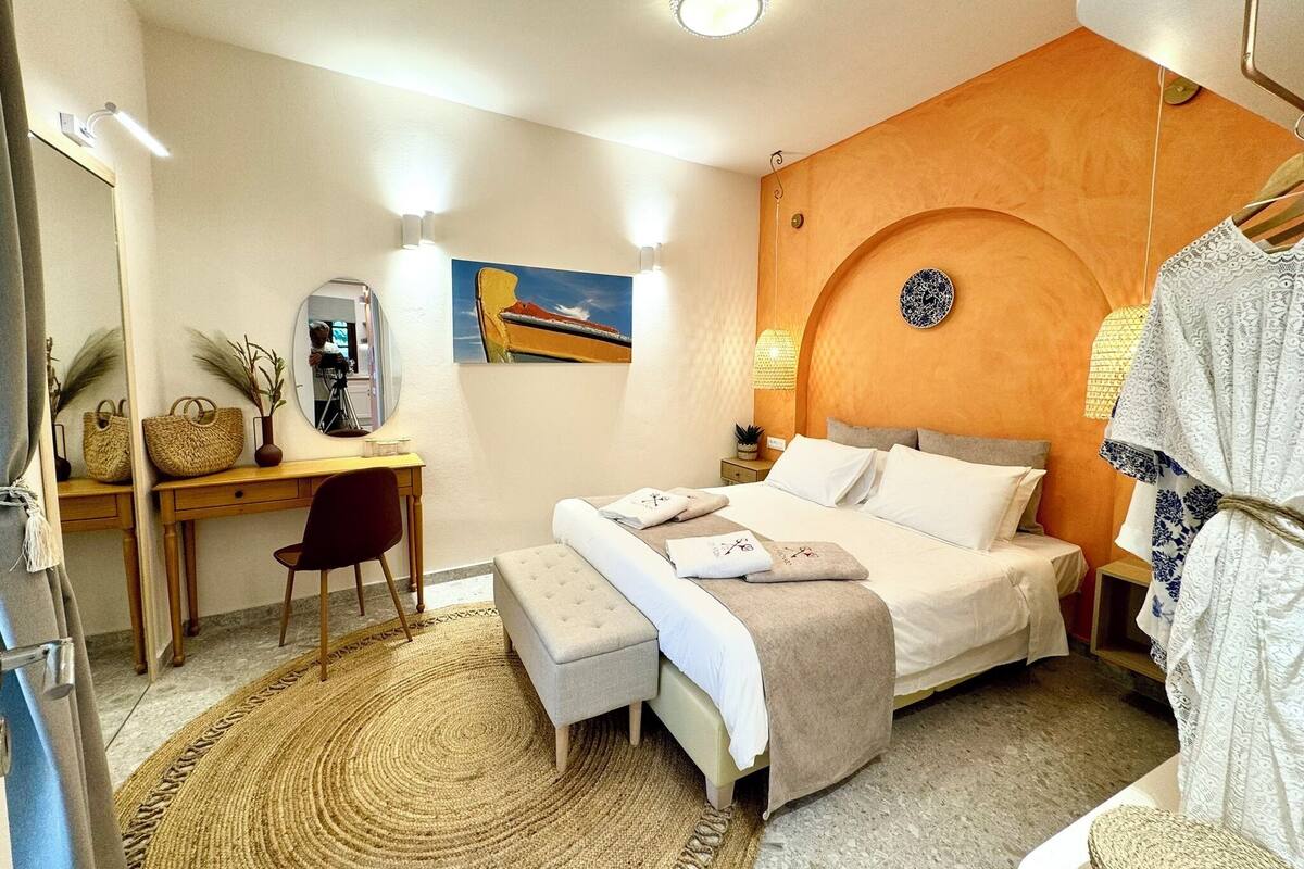 Ein Schlafzimmer mit Bett, Nachttisch, Stuhl, Schreibtisch und Spiegel.