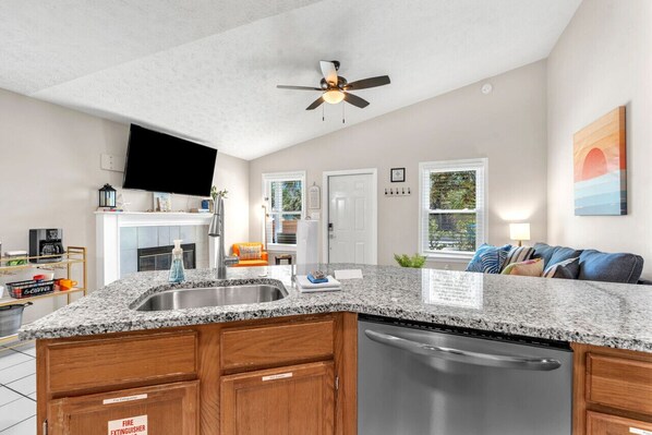 A modern kitchen with granite countertops, a dishwasher, and a ceiling fan.