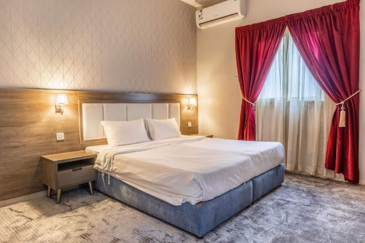 Un lit bien fait, avec du linge de lit blanc, une tête de lit en bois et deux lampes de chevet.