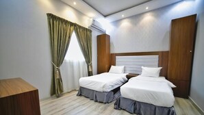 Una habitación de hotel con dos camas, un escritorio de madera y una ventana con cortinas.