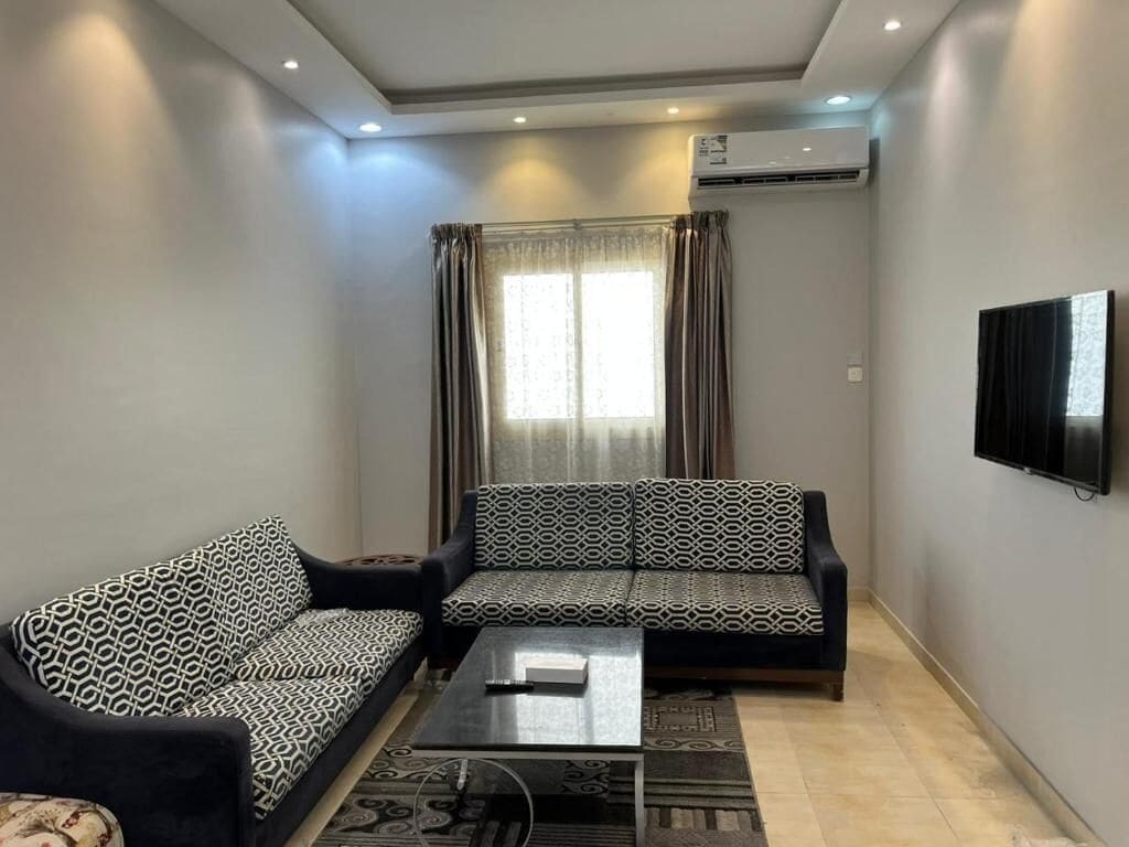 Una sala de estar con un sofá, una mesa de centro y un televisor montado en la pared.