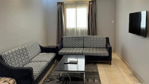 Una sala de estar con un sofá, una mesa de centro y un televisor montado en la pared.