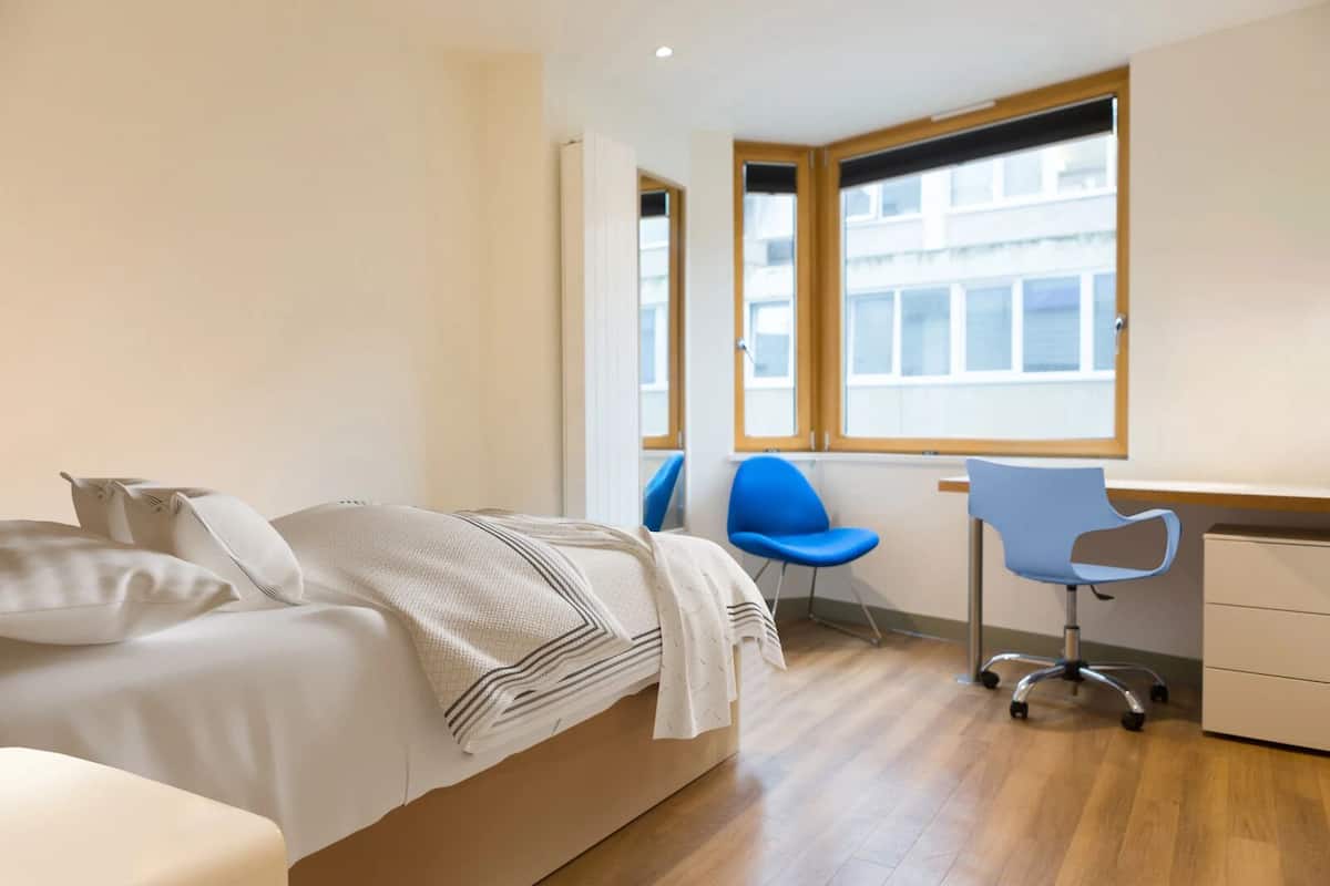 A modern bedroom with a bed, a desk, and two chairs.