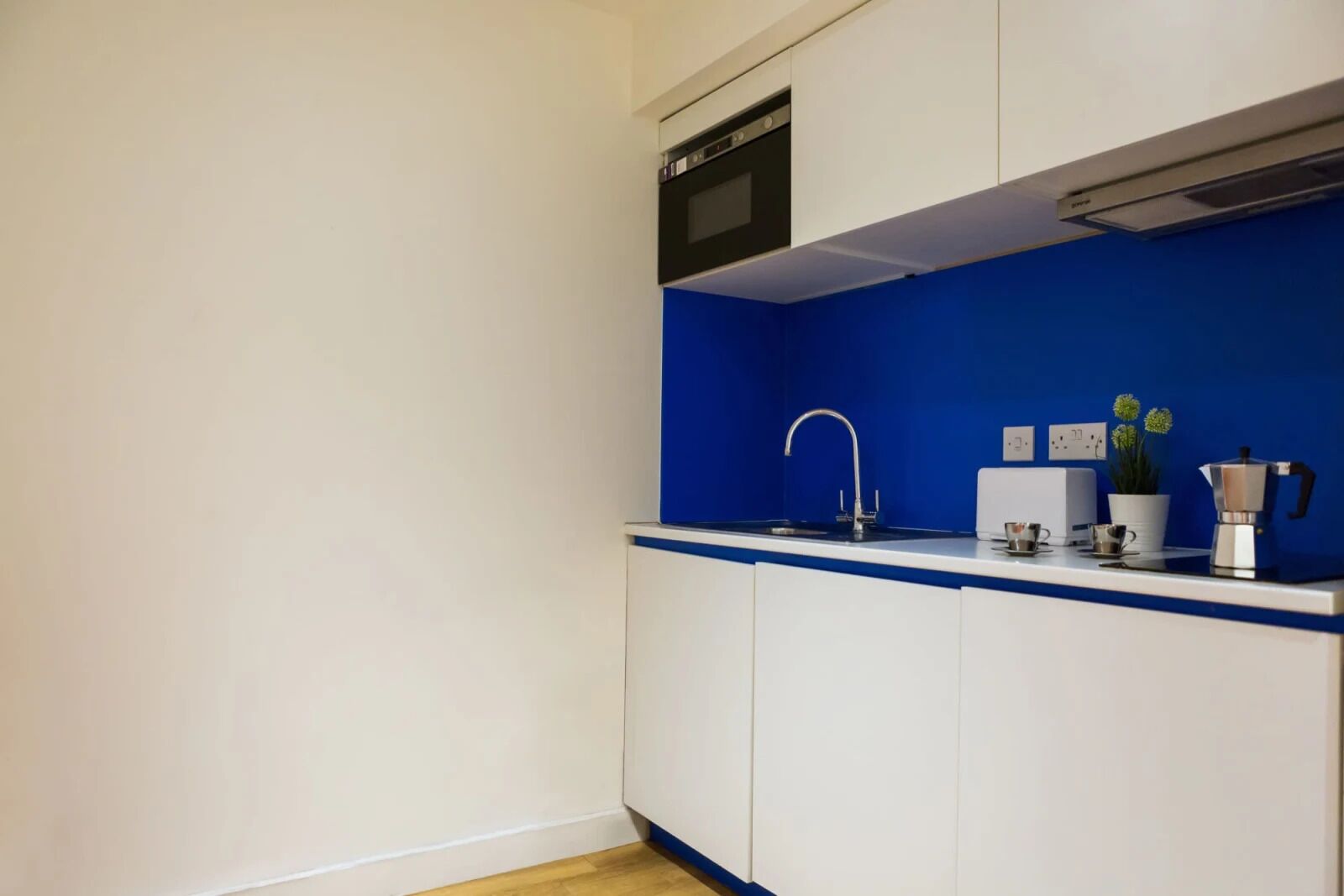 A compact kitchen with a built-in microwave, a sink, and a coffee maker.