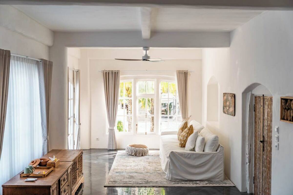 A spacious room with a large bed, a wooden bench, and a view of the outdoors through a window.