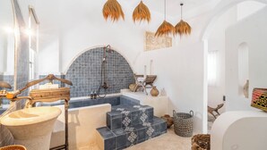 A bathroom with a bathtub, a sink, and a shower. There are wicker baskets and a wooden chair. - La Santa Rosa (Jimbaran)