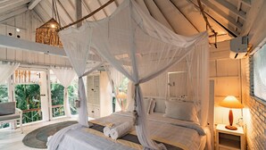 A bedroom with a canopy bed, a bedside table with a lamp, and a view of the outdoors. - La Santa Rosa (Jimbaran)