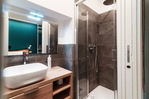 A modern bathroom with a large white sink, a mirror, and a glass-enclosed shower. - Just in Front (Cernobbio)