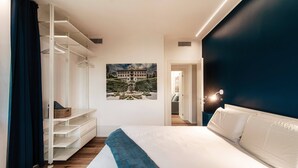 Een slaapkamer met een bed, een kledingkast, een schilderij en uitzicht op een gebouw door een geopende deur.