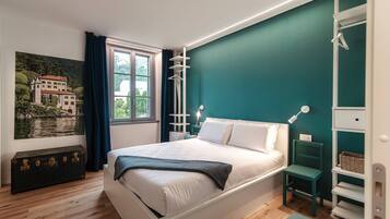 Un dormitorio con cama, una ventana con cortinas, un cuadro en la pared y una mesita de noche.