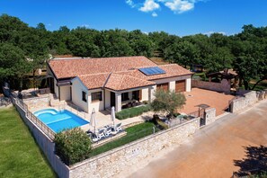 Relax by the outdoor pool surrounded by lush greenery and shaded patio areas.