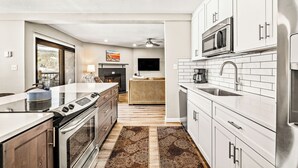 A modern kitchen with white cabinets, stainless steel appliances, and a central island. - Downtown Cozy Condo; Walk to town, Slopes & Hiking (Breckenridge)