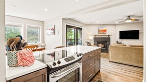 A modern kitchen with a large island, wooden cabinets, and a fireplace. - Downtown Cozy Condo; Walk to town, Slopes & Hiking (Breckenridge)