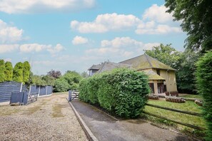 A residential property with a gravel driveway, a wooden fence, and a house with a sloped roof. - Spacious home 4 large families, contractors welcome (Wolverhampton)