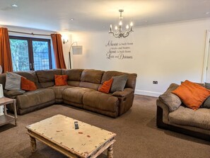 A living room with a sectional sofa, a smaller sofa, a coffee table, and a chandelier. - Spacious home 4 large families, contractors welcome (Wolverhampton)