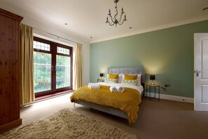 Un dormitorio con cama, un candelabro, una ventana con cortinas y una puerta.