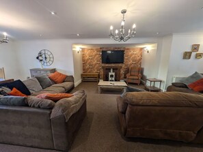 A living room with a fireplace, sofas, a coffee table, and a television.