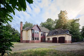 Ein großes, zweistöckiges Gebäude mit roter und beiger Fassade, zahlreichen Fenstern und einem Ziegelkamin.