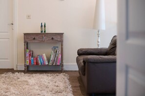 A room with a bookshelf, a leather sofa, and a fluffy rug.