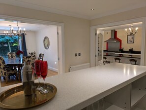 Una cocina moderna con mostrador, una zona de comedor con mesa y sillas, y vistas al exterior.
