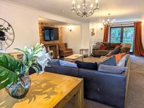 Una sala de estar con sofá, mesa de centro, chimenea y televisor.
