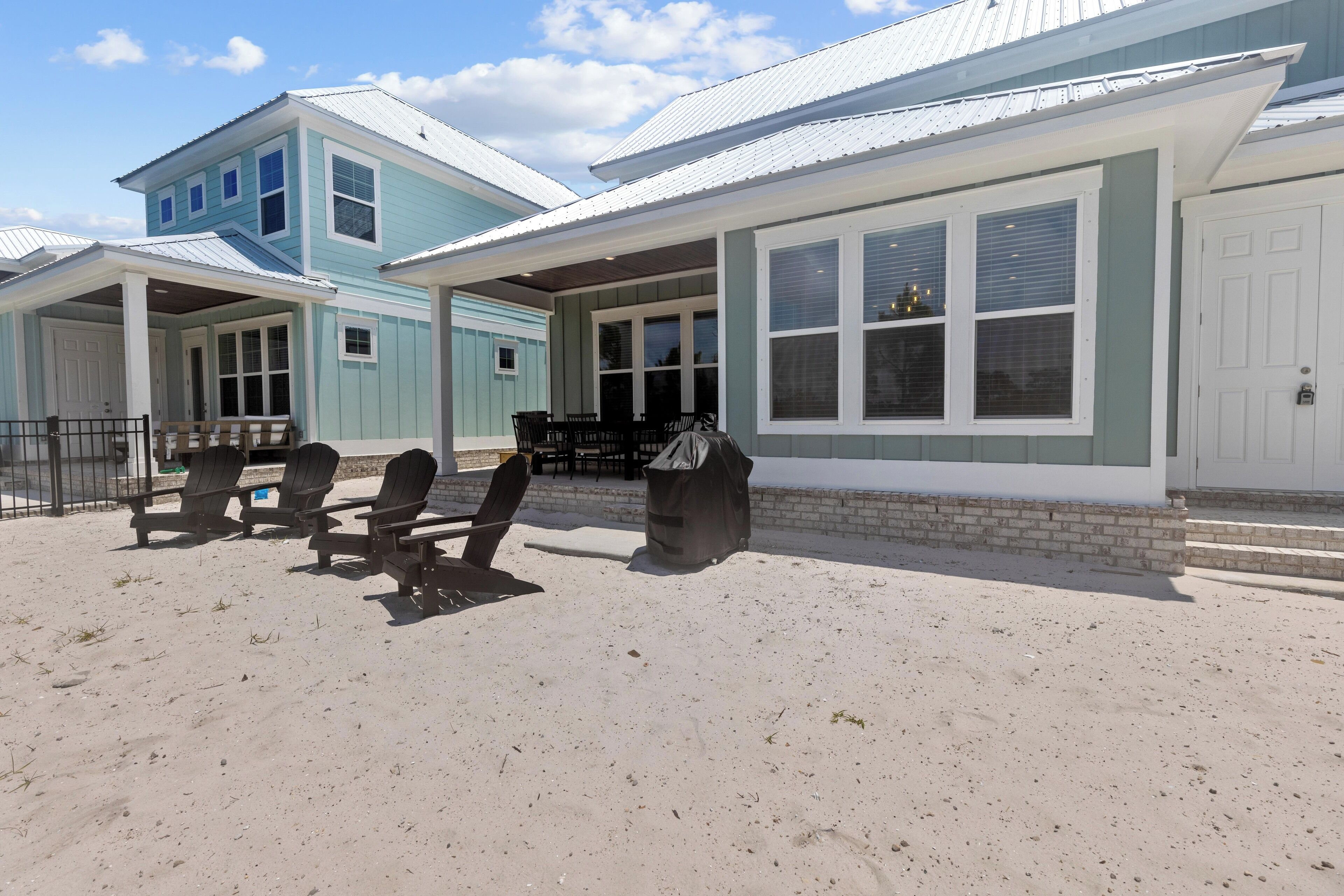 Une propriété située en bord de mer, dotée d’un patio couvert, d’un espace salon extérieur et d’une grande fenêtre donnant sur la plage.