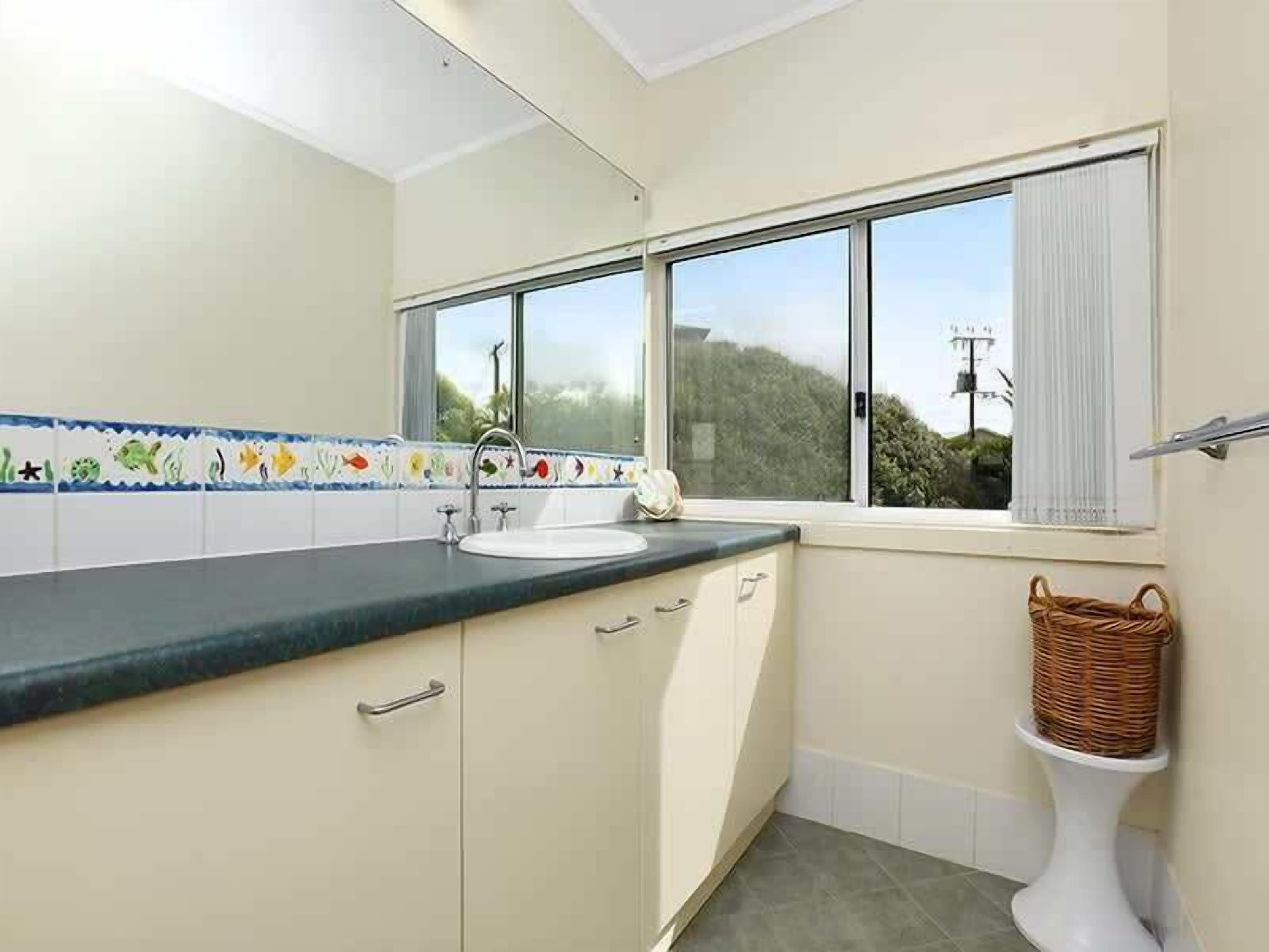 Una cocina con ventana, un lavabo y una cesta.