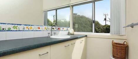 Una cocina con ventana, un lavabo y una cesta.