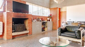 Un salon moderne avec une cheminée en briques, une table basse en verre et un canapé en cuir.