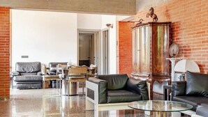 Un salon moderne avec des canapés en cuir, une table basse en verre et un mur en briques.
