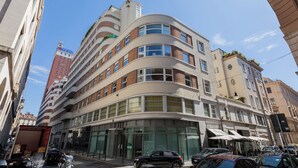 A multi-story hotel with a curved facade, large windows, and a visible entrance with a glass door. - Elegant Home with Terrace by Wonderful Italy (Turin)