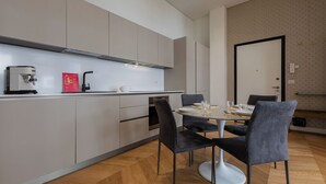 A modern kitchen with a coffee machine, a sink, and a dining area with a round table and chairs. - Elegant Home with Terrace by Wonderful Italy (Turin)