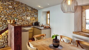 Una cocina moderna con pared de piedra, mesa de comedor de madera y sillas.