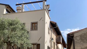 Una estrecha calle adoquinada flanqueada por edificios tradicionales de paredes de piedra y contraventanas de madera.