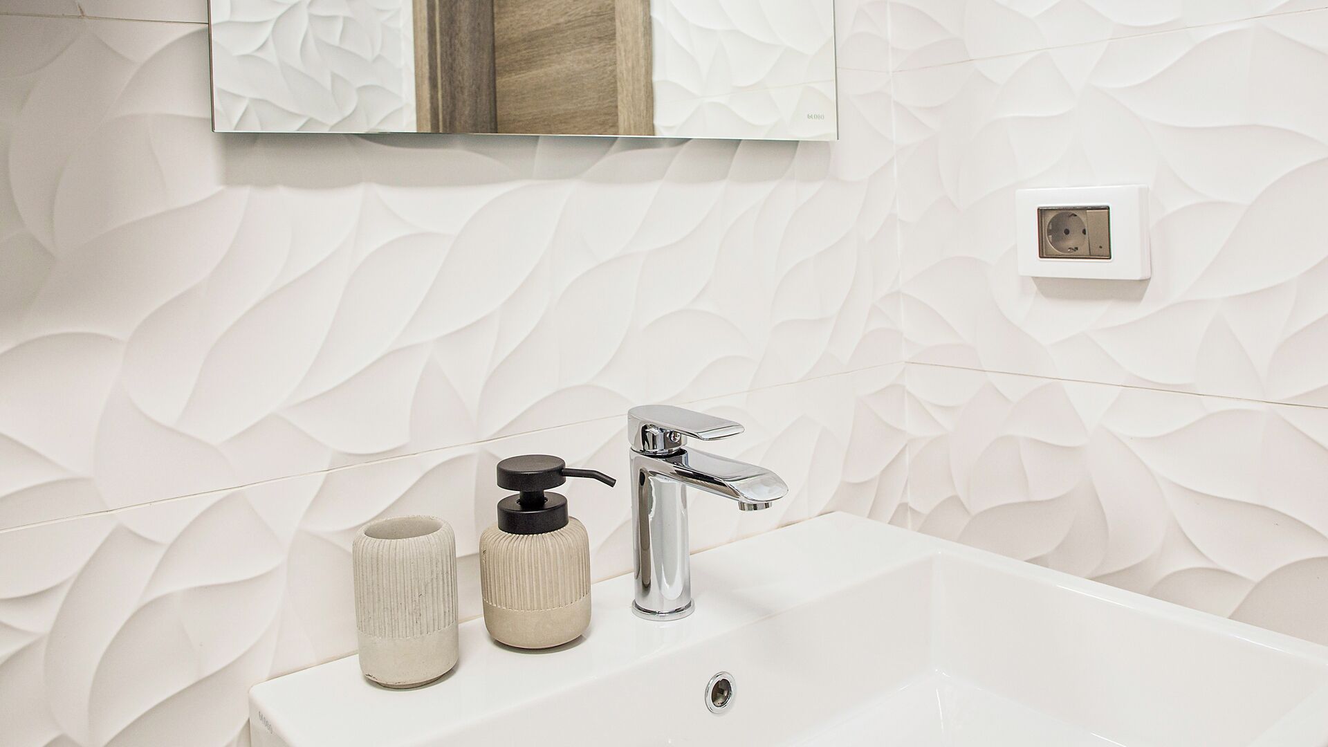 Une salle de bain avec un lavabo blanc, un robinet chromé et un mur à texture.
